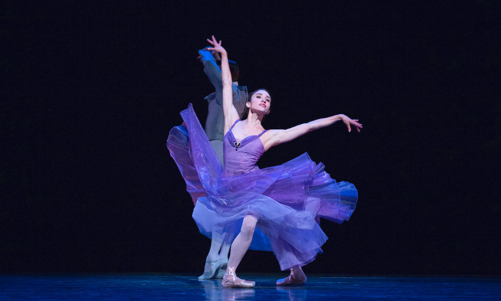 Dancer Leta Biasucci lands in a deep fourth position, arms splayed, in a shimmering purple dress.
