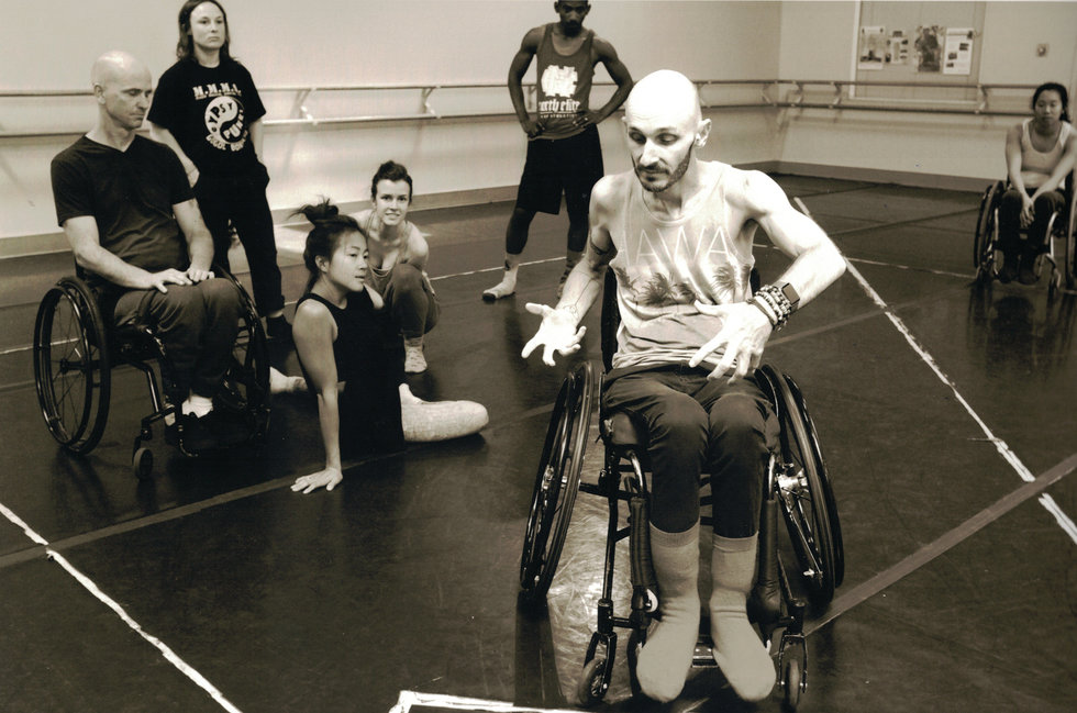 Marc Brew, in a wheelchair, leads a company of dancers, some of whom are also in wheelchairs