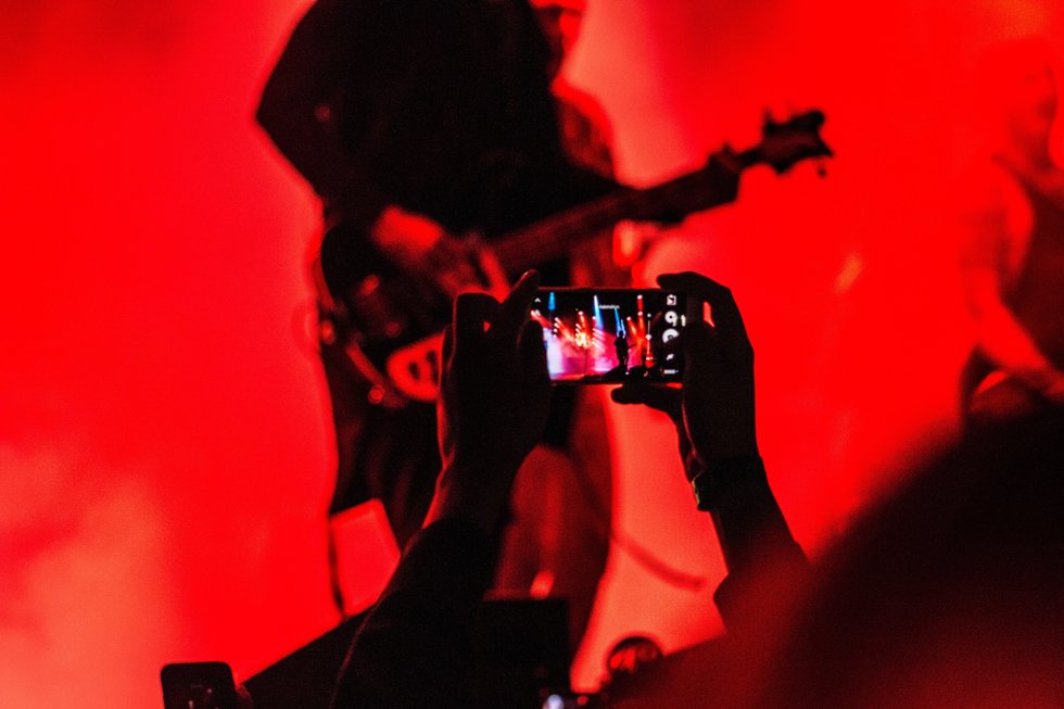 Person in crowd videotaping guitarist