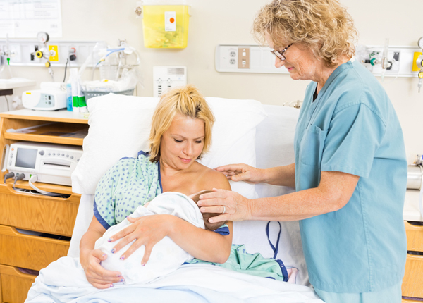 woman breastfeeding newborn in hospital