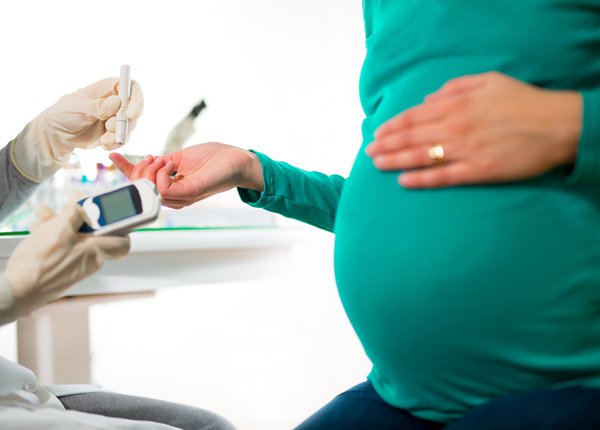 pregnant woman testing her blood sugar