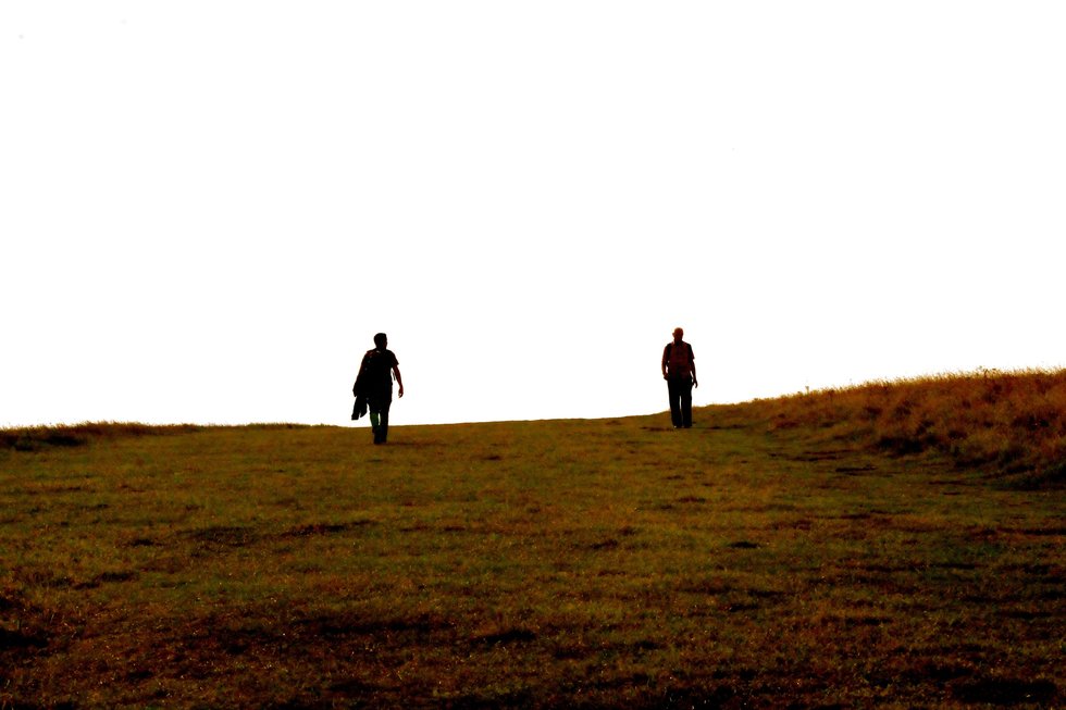 Two people walking up a hill of some kind