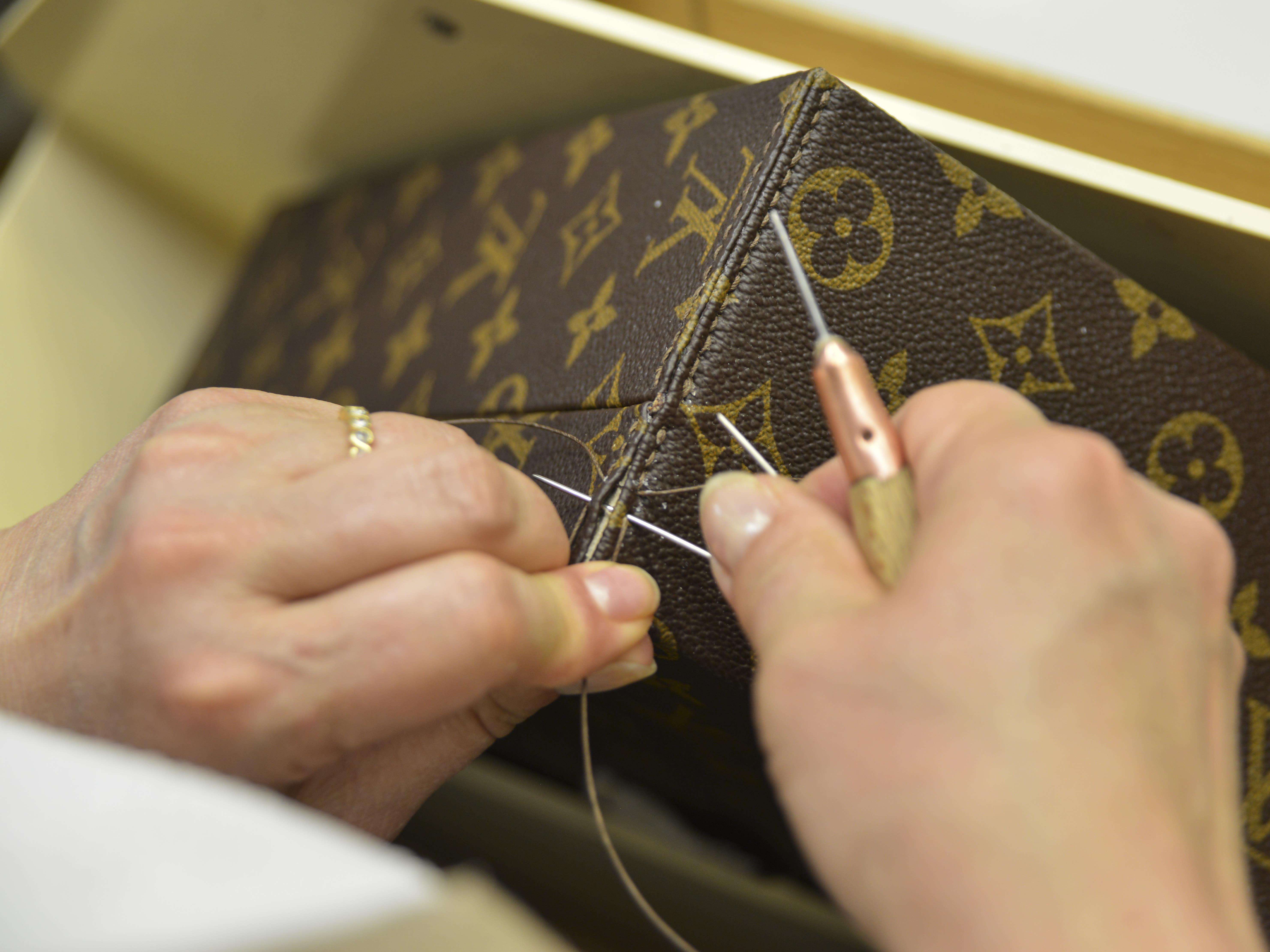 A worker cuts the distinctive LV logo fabric of natural cowhide leather  without using a ruler. He says he has been on the job here since 1988. The  interlocking chocolate brown and