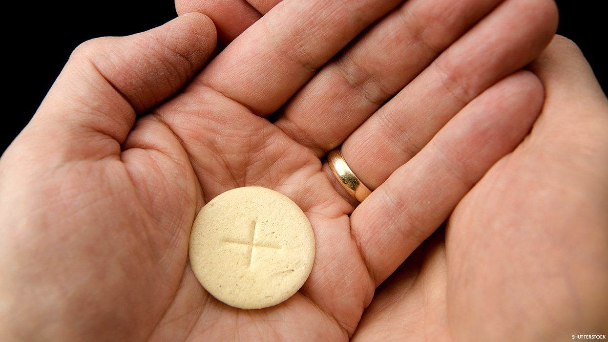 Hands with open palms receiving a communion wafer.