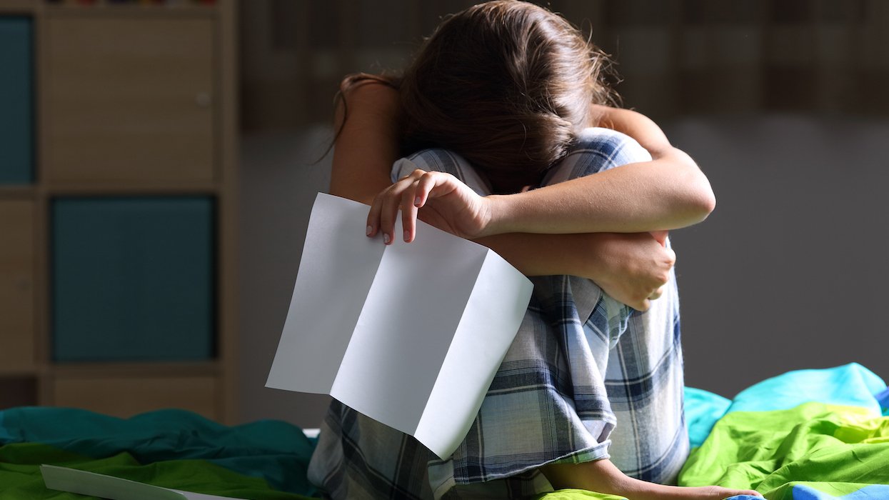 Girl, sad, holding her legs in bed