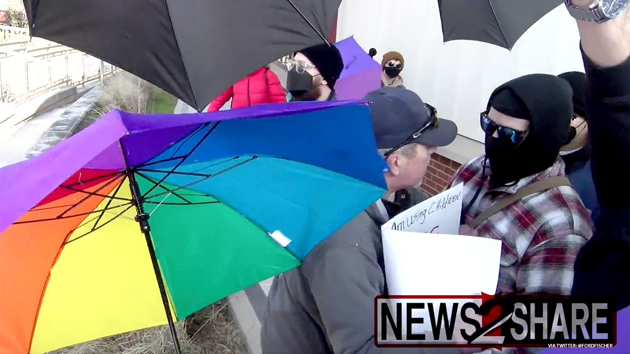 A man is having a contentious conversation with a person holding a sign.