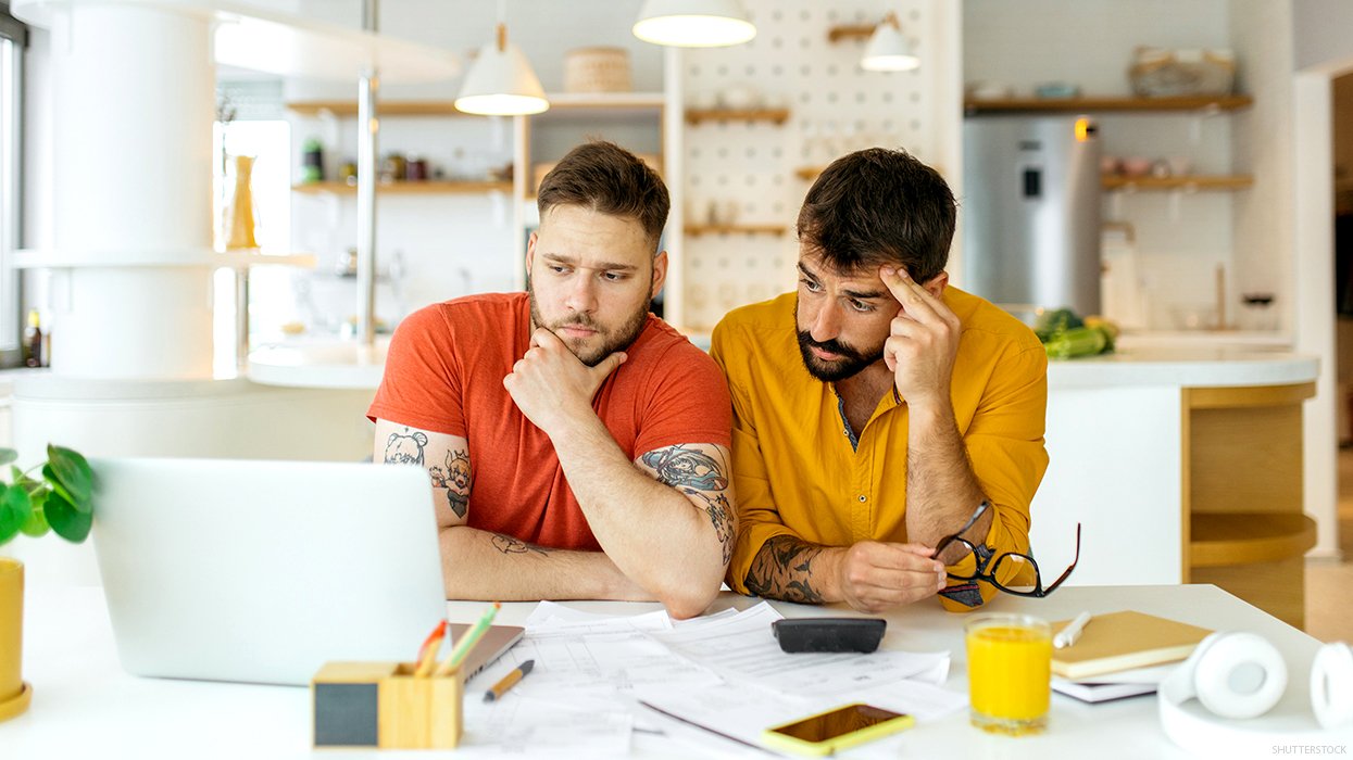 Two men looking at a computer with concern on their faces.