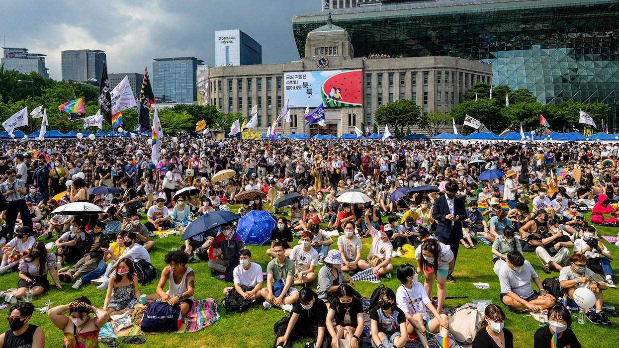 SQCF event in Seoul — hundreds of people sitting on a green law with rainbow flags