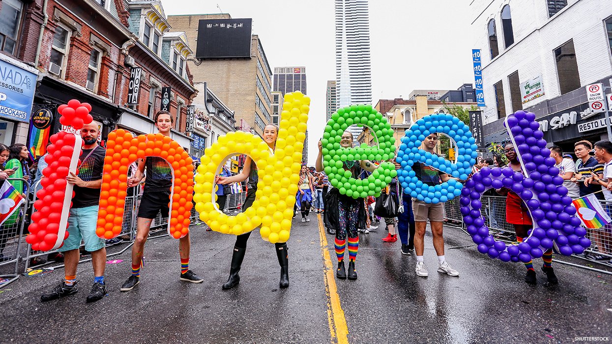 People walking in a parade holding a rainbow colored indeed logo in the letters that make up the word.