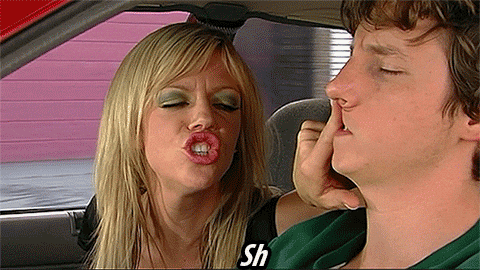gif of a woman shushing a man while he drives