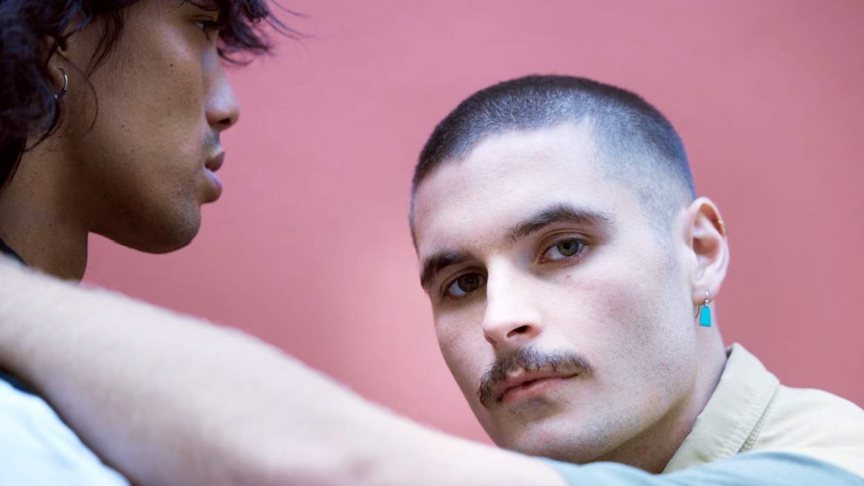 Two men, with one looking at the camera while the other looks past the other