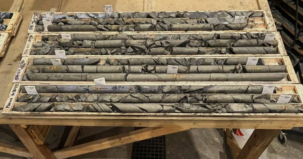 Nine Mile Metals' Drill core samples displayed in wooden boxes on a table.