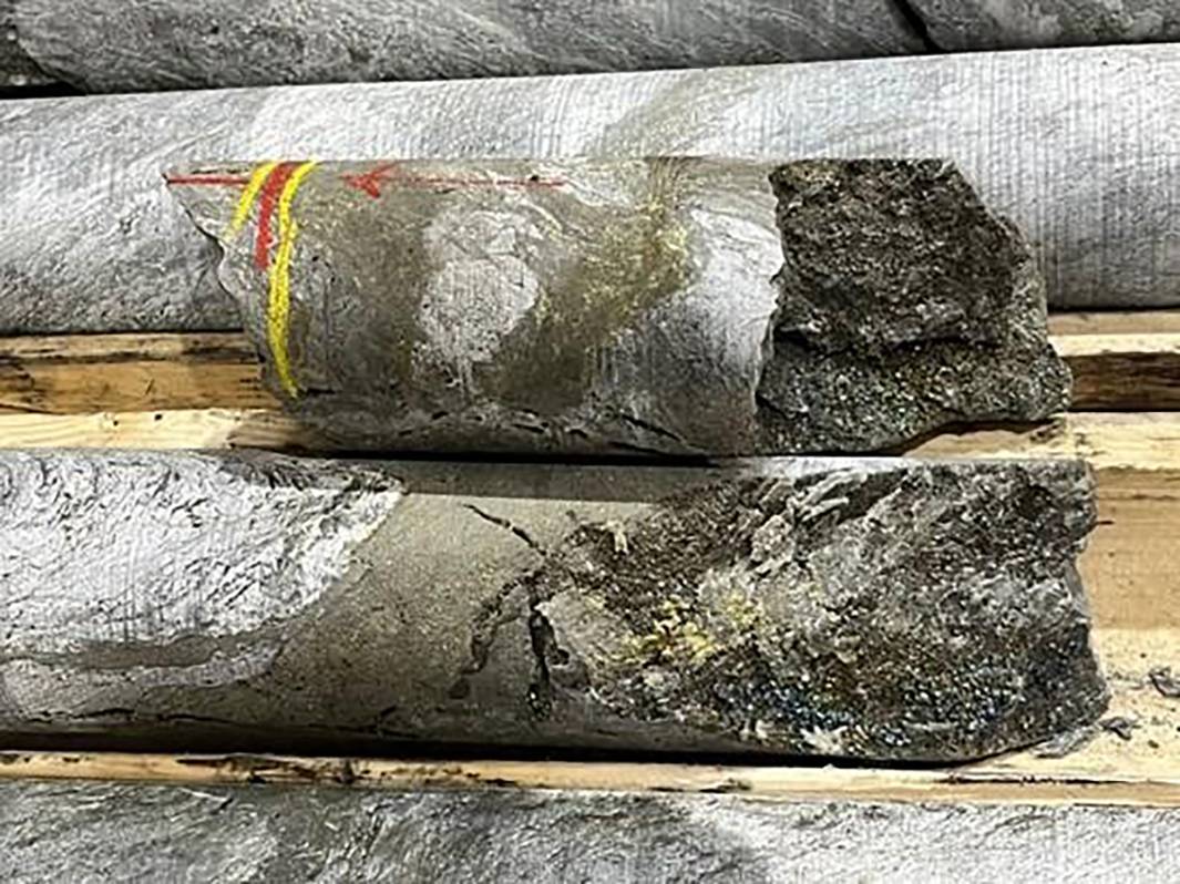 Nine Mile Metals' close-up of drilled core samples with colored markings on rough wooden planks.