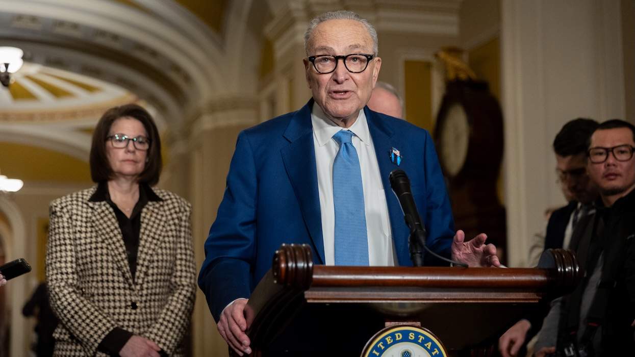 ​Sen. Chuck Schumer with several people around him at a podium speaking