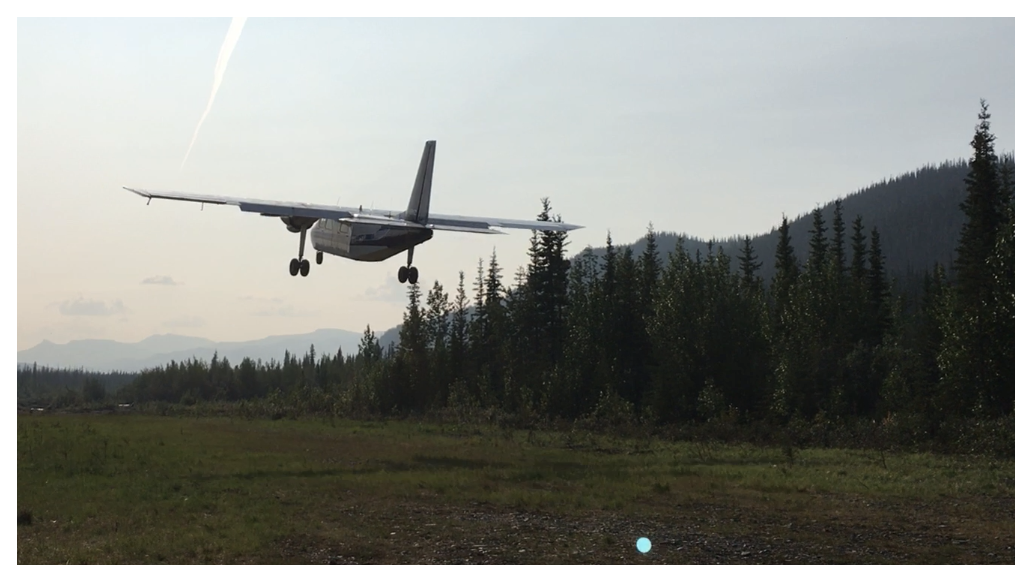Small plane landing in a forested area with mountains in the background at Flow Metals' Monster IOCG project