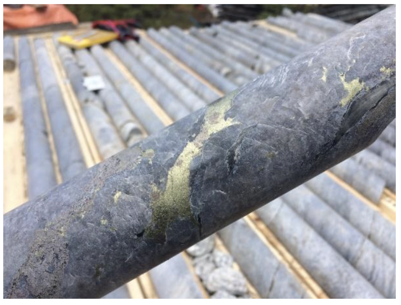 Oreterra Metals' close-up of a rock core sample with metallic mineral streaks, stacked on a wooden rack.