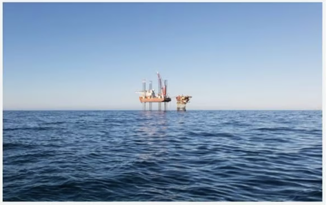BPH Energy offshore oil platform on the horizon under a clear blue sky, surrounded by calm ocean water.